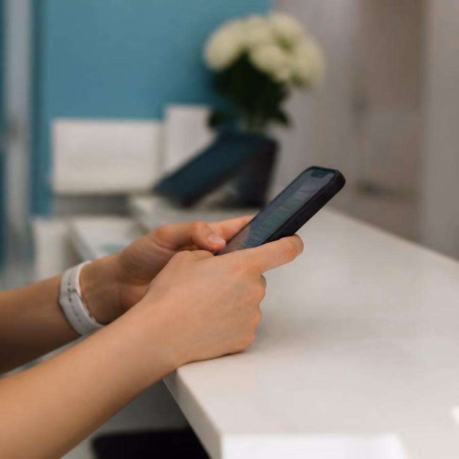 Recepcionista de consultorio médico respondiendo a un paciente por WhatsApp desde su smartphone