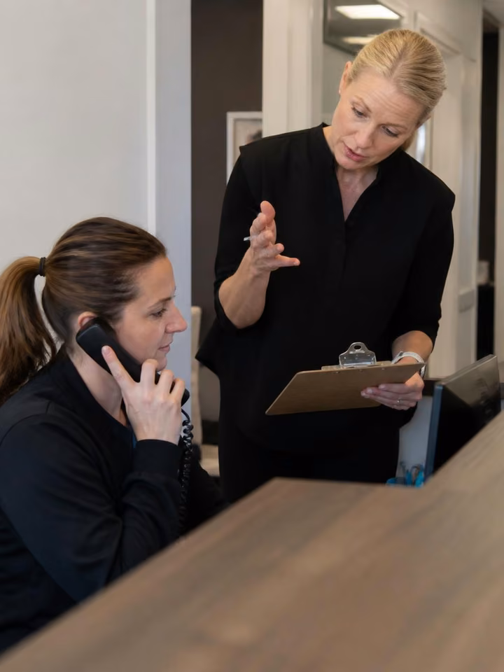 Coach comercial entrenando a una recepcionista de consultorio médico en un ejercicio de atención telefónica